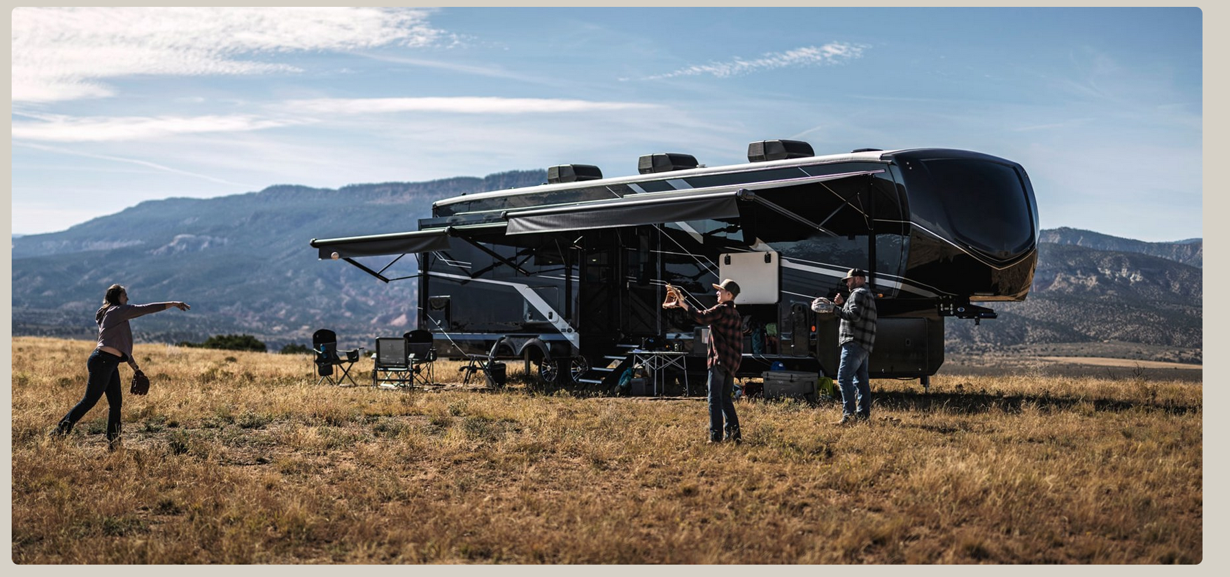 Family playing catch standing on sprawling plains in front of a Mountain range and RV